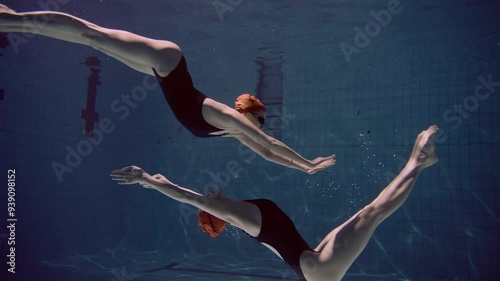 Two Young women with orange swimming cap underwater