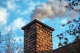 Smoke is coming out of a brick chimney on a sunny day