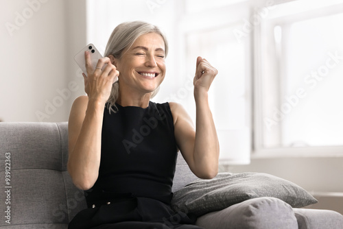 Fotografie Woman spend time at home with smartphone, get message, feels unbelievable excited, read notification about dream job, long awaited special offer, win on-line lottery