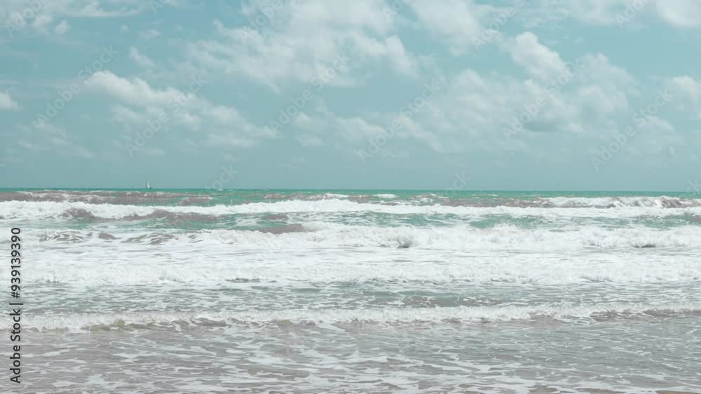 Turquoise ocean waves crashing on sunlit beach create tranquil atmosphere.distant sailboat glides across horizon, enhanc picturesque coastal view in slow motion Turquoise ocean waves crashing on sunlit beach create tranquil atmosphere.distant sailboat glides across horizon, enhanc picturesque coastal view in slow motion