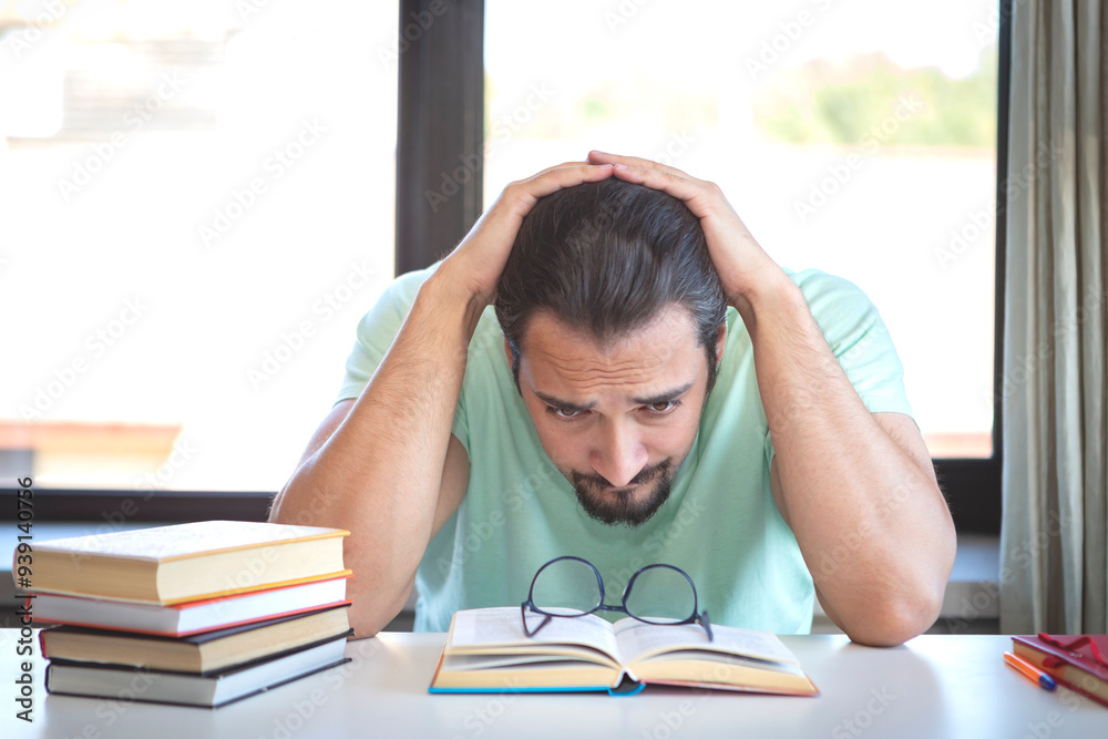 Tired and bored student sitting at the desk while preparing for exams at university Tired and bored student sitting at the desk while preparing for exams at university