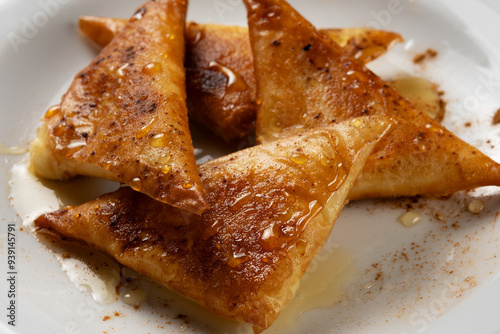 Closeup mini cheese pies with myzithra, cretan honey and cinnamon.