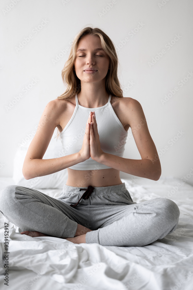 Woman training yoga and fitness in lotus pose for zen, mental health, meditation in peace to relax on the bed at home Woman training yoga and fitness in lotus pose for zen, mental health, meditation in peace to relax on the bed at home