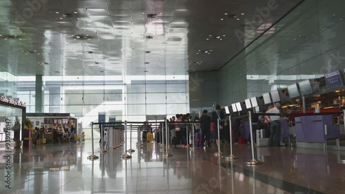 A large airport terminal with people waiting in line. Scene is busy and bustling