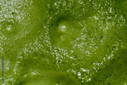 A close-up image of Smooth surface of green tea, frothy texture. The vibrant green color and visible air bubbles on the surface highlight the freshness and quality of the matcha