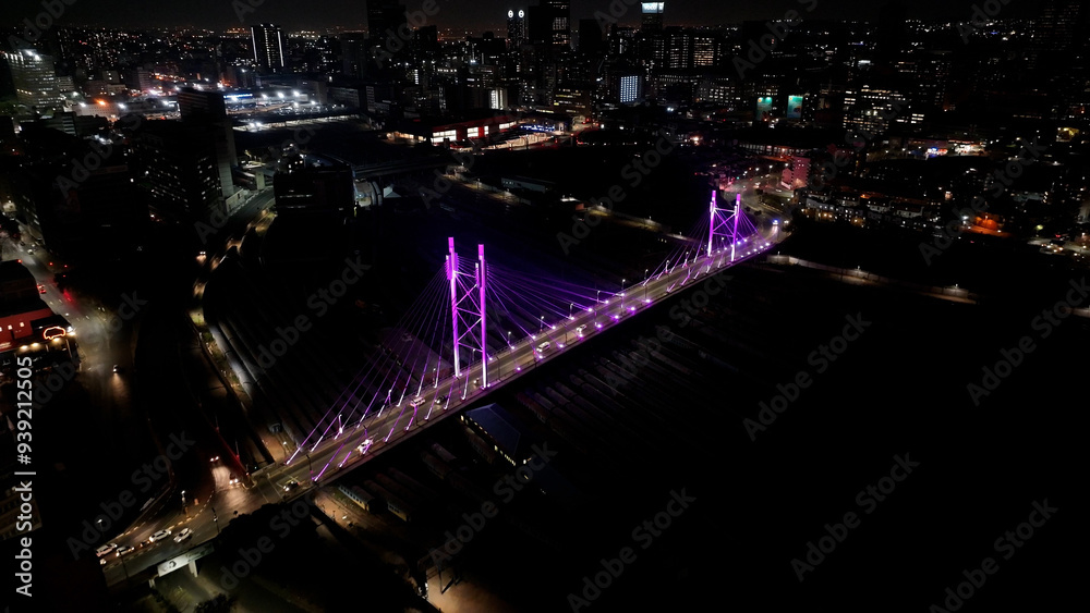 Obraz premium Nelson Mandela Bridge At Johannesburg In Gauteng South Africa. City At Night Landscape. Illuminated Cable Bridge. Johannesburg At Gauteng South Africa. Landmark Buildings. Colored Bridge.
