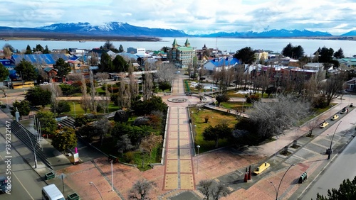 Plaza De Armas At Puerto Natales In Magallanes Chile. Snowy Mountains. Square Scenery. Magallanes Chile. Buildings Landscape. Plaza De Armas At Puerto Natales In Magallanes Chile. photo