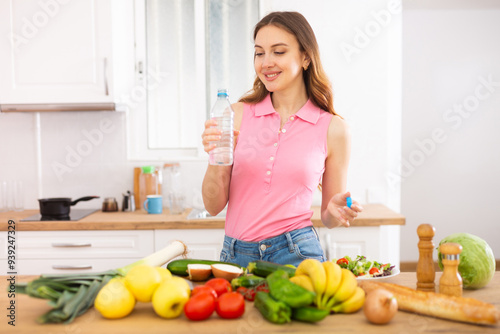 Slim woman drinking clean water in cozy kitchen home