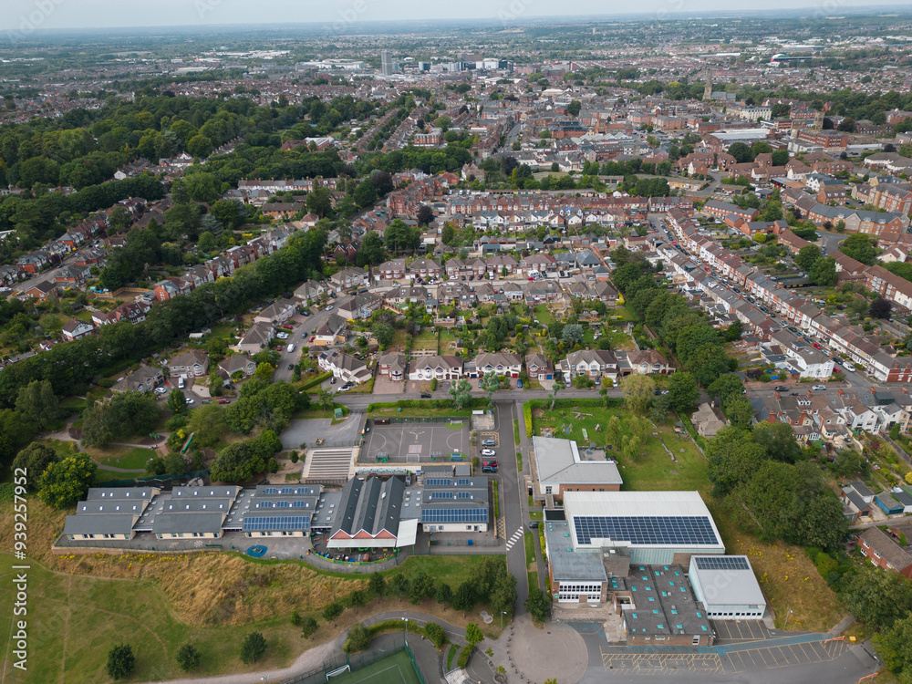 Green energy with solar panels on the roof of primary school in Swindon UK. Aerial view on neighborhood with houses and gardens in old town. Panoramic view towards town center.