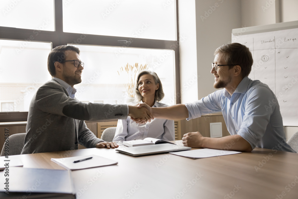 Obraz premium Two businessmen shaking hands finish meeting in office, congratulate each other on their achievements and professional success, make deal, establish partnership. Positive interaction, goodwill gesture