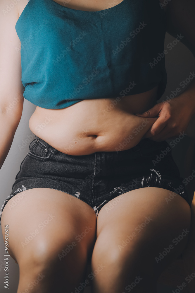 Fototapeta premium fat woman, fat belly, chubby, obese woman hand holding excessive belly fat with measure tape, woman diet lifestyle concept