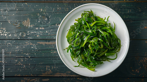 White plate with tasty wakame chuka seaweed salad on old wooden table, top view photo