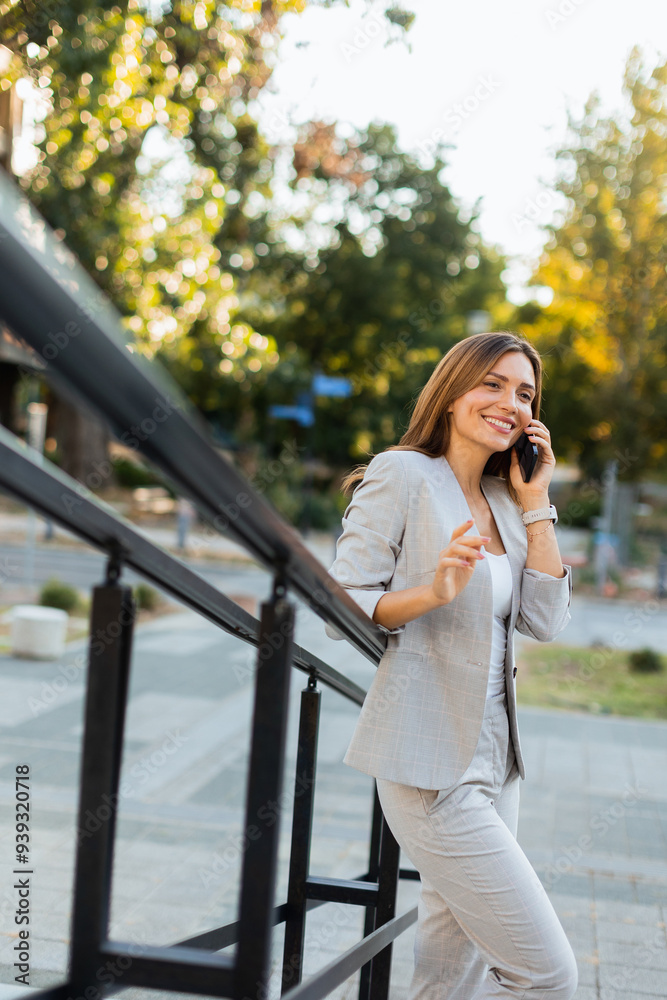 Woman enjoys a sunny outdoor stroll while engaged in a lively phone conversation, exuding confidence in a stylish gray outfit Woman enjoys a sunny outdoor stroll while engaged in a lively phone conversation, exuding confidence in a stylish gray outfit