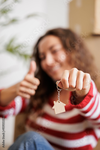 Smiling single young woman with the keys to her new house in her hand, close up shot.