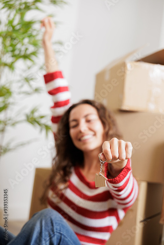 Smiling single young woman with the keys to her new house in her hand, close up shot.