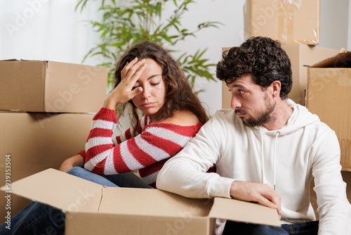 Two sad evicted tenants move home with their belongings sitting on the floor. Exhausted and exhausted couple after finishing the move to their new house. photo