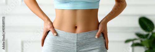 Close-up of a woman's toned midsection in workout attire. Fitness, health, and active lifestyle concept with neutral background.
