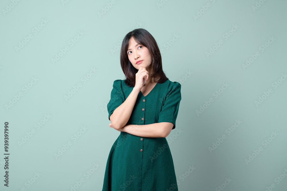 Thoughtful woman in green dress, pondering with curious expression. Thoughtful woman in green dress, pondering with curious expression.