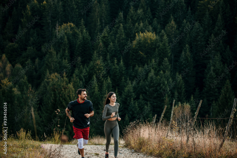 Fototapeta premium Shot of a young couple admiring view while out for a workout on a mountain road