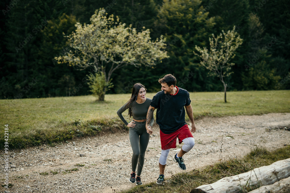 A young man and woman in sportswear talking and laughing while running together in a park A young man and woman in sportswear talking and laughing while running together in a park