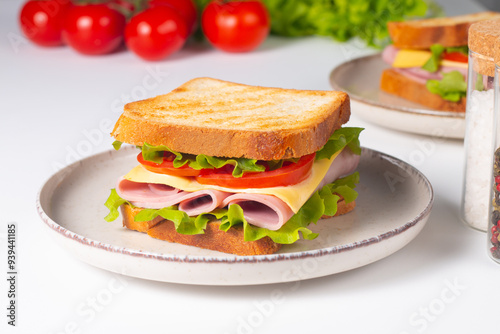 Close-up of two sandwiches with bacon, salami, prosciutto and fresh vegetables on rustic wooden cutting board. Club sandwich concept