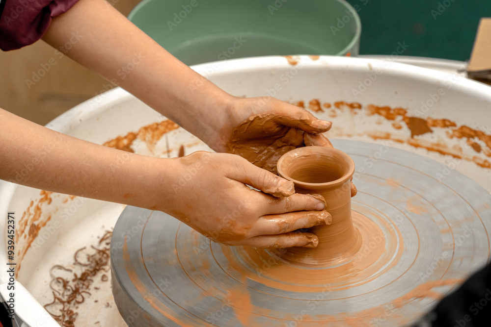 Children's hands create pottery on a potter's wheel during a master class on an outdoor playground Children's hands create pottery on a potter's wheel during a master class on an outdoor playground
