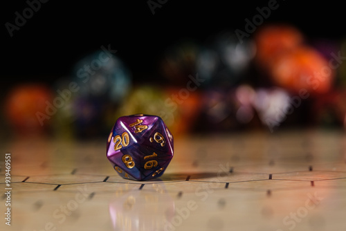 a blue and purple marbled twenty-sided D20 dice with gold numbers, showing the number 20, sitting on a hexagonal tabletop gaming board with a variety of different types of dice in the background. 