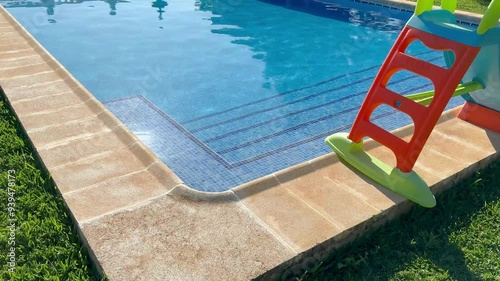 Sunlit swimming pool with a colorful slide.