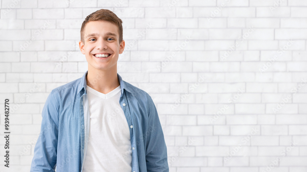 Portrait of handsome smiling guy posing over white brick wall Portrait of handsome smiling guy posing over white brick wall