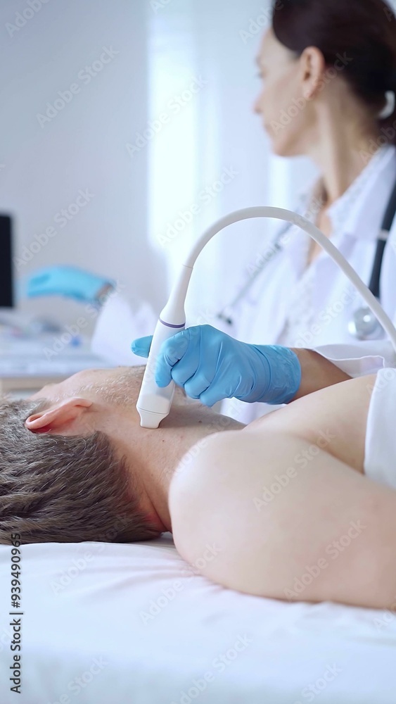 Obraz premium Doctor woman wearing blue medical gloves performing neck ultrasound exam on male patient. Medicine service concept