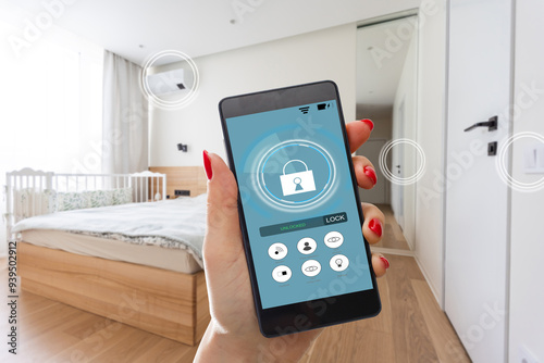 Young woman holding smart phone with launched security application at home. Concept of controlling and managing home security from a mobile device photo