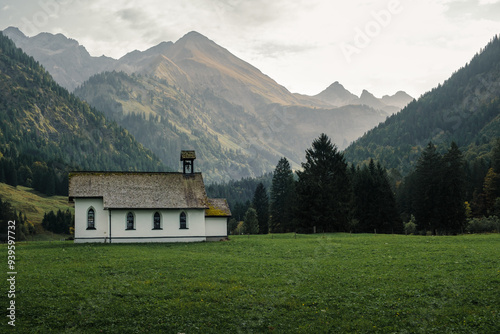 View of a small white church in Stillachtal in Germany. In the background, the Trettachspitze and Mädelegabel mountains near Birgsau. photo