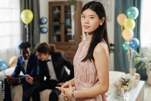 Woman standing in front of friends sitting on sofa at home celebrating special occasion photo