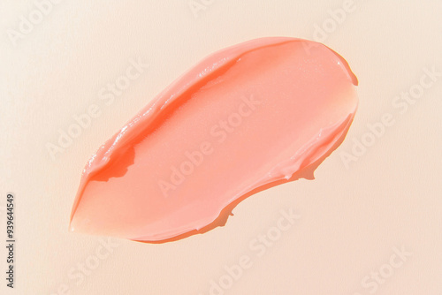 Peach hair conditioner smear on a light beige background. Smooth lip gloss, balm or shower gel texture.