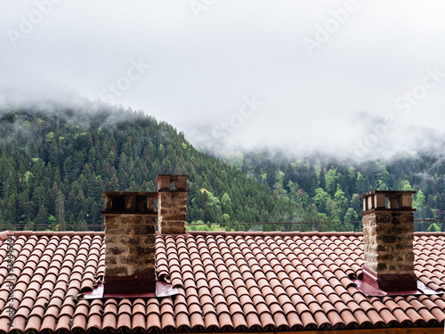 tiled roof with chimney and gray cloud on mountain photo