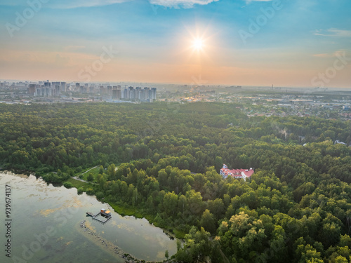 Big lake with green shores in bright sun light and city on horizon, aerial landscape. Recreation concept. Aerial view photo