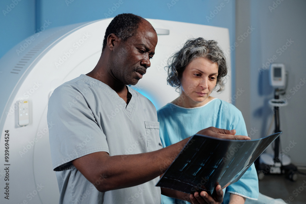 Medical professionals analyzing MRI scans with focus on detailed observation and discussion of scan results in clinical environment Medical professionals analyzing MRI scans with focus on detailed observation and discussion of scan results in clinical environment
