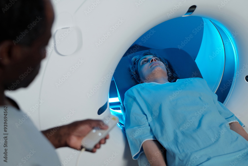 © TrueFrame Collective - Person lying inside MRI scanner receiving diagnostic imaging with medical personnel operating machine nearby © TrueFrame Collective - Person lying inside MRI scanner receiving diagnostic imaging with medical personnel operating machine nearby