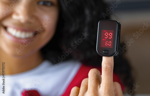 Happy African American woman with portable pulse oximeter on a finger measuring blood oxygen levels and pulse. Healthcare concept photo