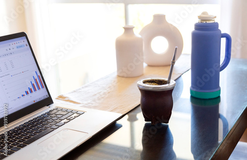 Working and drinking yerba mate. Gourd mate with yerba inside, over the table next to a laptop in workplace.