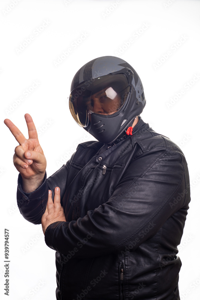 Biker, an adult man in black biker clothing and helmet in front of a white background, selective focus. Biker, an adult man in black biker clothing and helmet in front of a white background, selective focus.