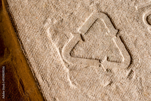 Close-up of embossed recycling symbol on cardboard. Close-up shot of an embossed recycling symbol on a cardboard surface, highlighting sustainable packaging and eco-friendly materials.

