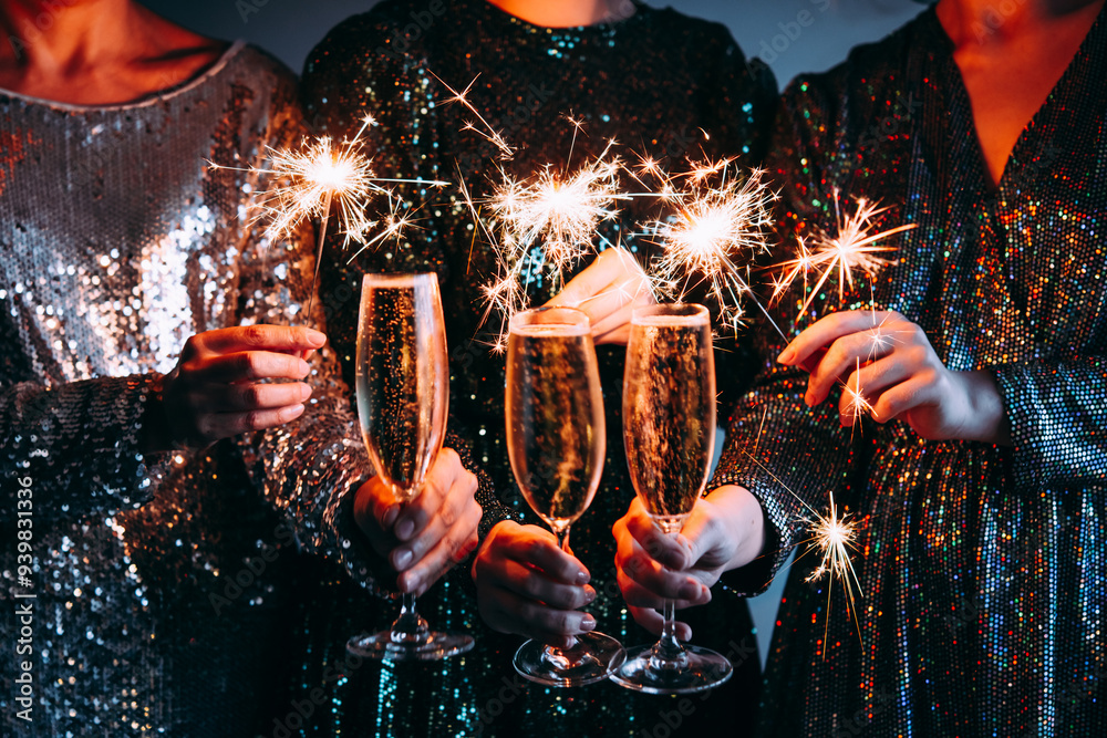 Friends celebrating Christmas or New Year eve party with Bengal lights and champagne.