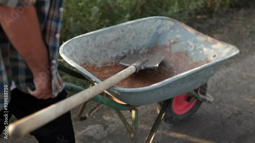 Wallpaper Mural Close-Up of an Elderly Farmer Pushing Wheelbarrow on Dirt Road Near Field Torontodigital.ca