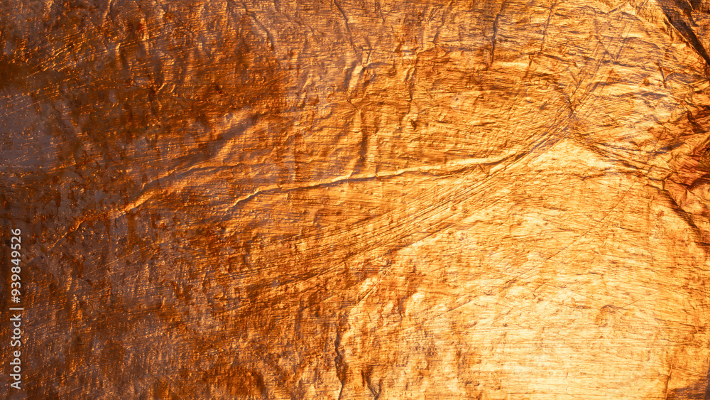 Fototapeta premium Closeup of crumpled gold foil reflecting light and creating an uneven, textured surface