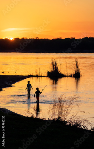 On a camping trip to Oklahoma state park. We saw this beautiful sunset near a lake. Two boys played with each other in the water. Sunset lit up the whole sky. 