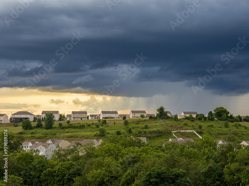 Dramatic storm clouds hanging over a US residential neighborhood with bright gap in the sky on a summer evening.