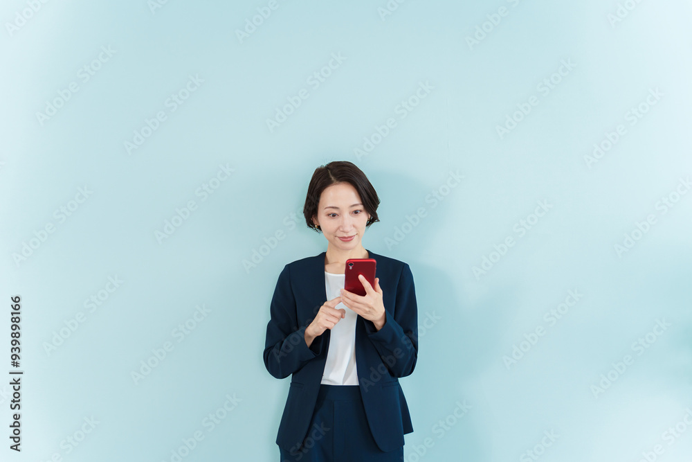 スマートフォンを使うビジネスウーマン ブルーバック スマートフォンを使うビジネスウーマン ブルーバック