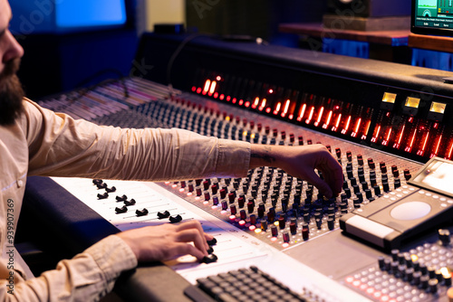Audio editor changes and blends records to create fresh tracks, adding sound effects to boost audio recordings quality. Music production expert working in professional studio control room.