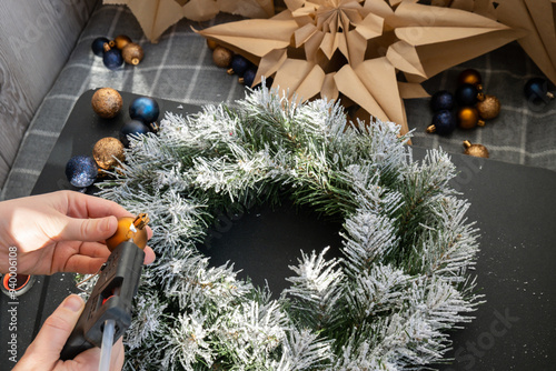 Crafter using hot glue Handmade Christmas wreath from festive blue and yellow decorations. Festive holiday preparation craft master class of creative making decor. Hands-on activities sustainable photo